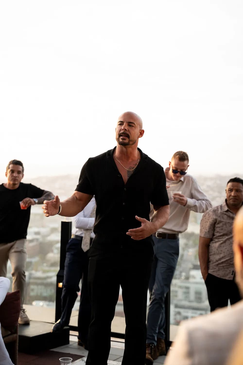 Garin Heslop speaking to a group of men on a rooftop, the city behind them
