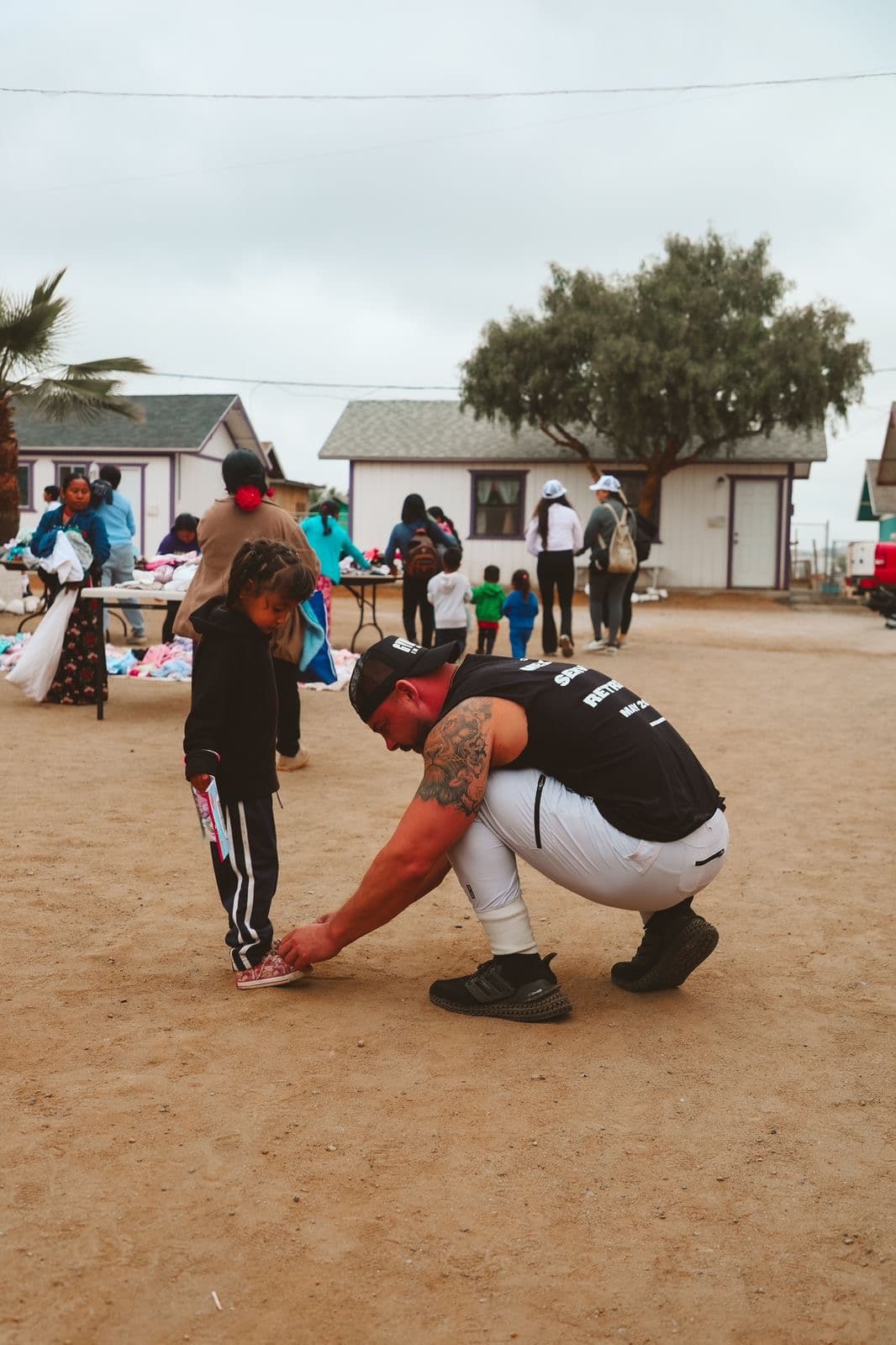Garin Heslop kneeling to tie a child's shoe at the Mexico Service Retreat